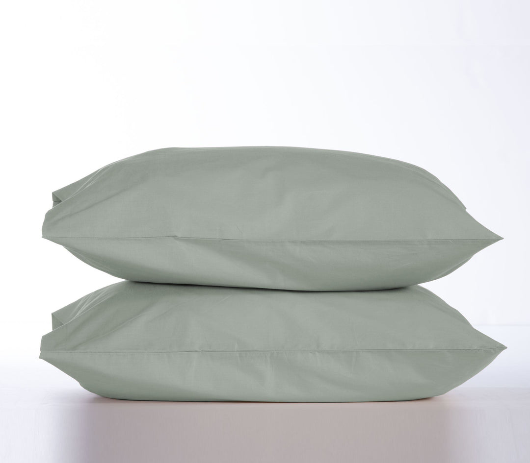 Δύο μαξιλαροθήκες σε απόχρωση πράσινου τοποθετημένες η μία πάνω στην άλλη σε λευκό φόντο, με καθαρό και minimal σχεδιασμό.