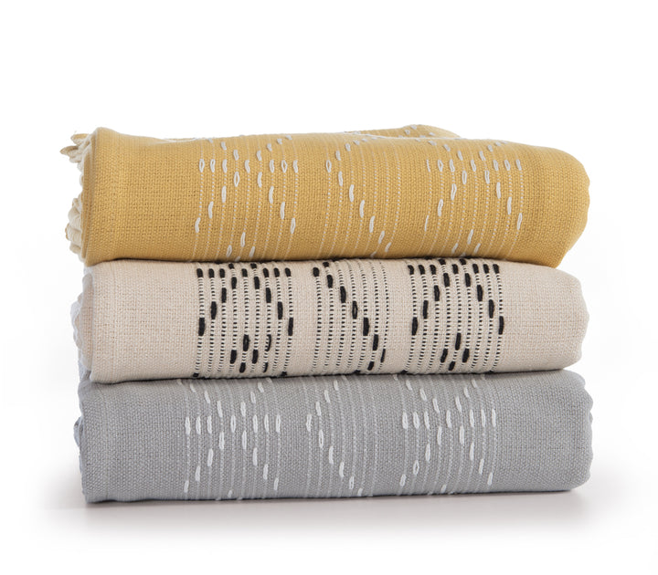 Στοίβα από τρία ριχτάρια με γεωμετρικά μοτίβα, σε μουσταρδί, εκρού με μαύρο και γκρι με λευκό χρώμα.