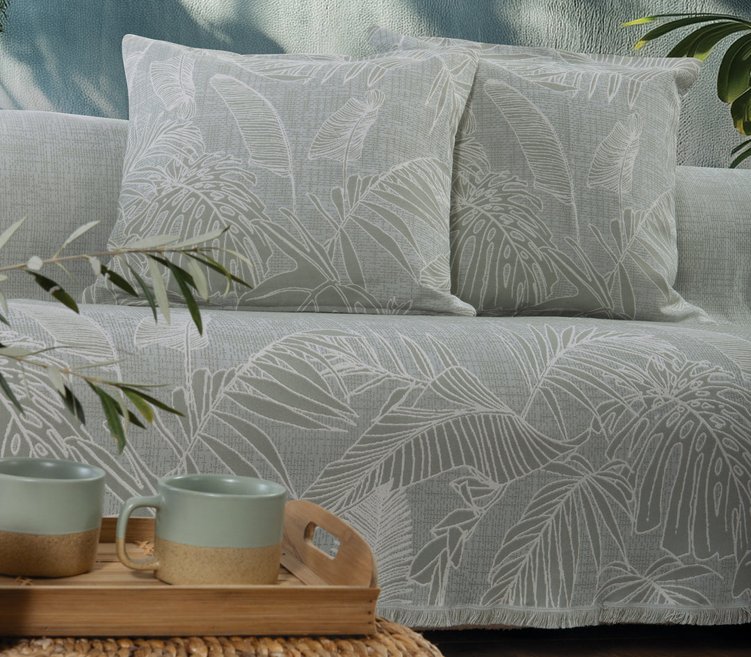 Κοντινή λήψη ριχταριού σε απαλό πράσινο χρώμα με λευκά φυλλώδη μοτίβα και ασορτί διακοσμητικά μαξιλάρια.