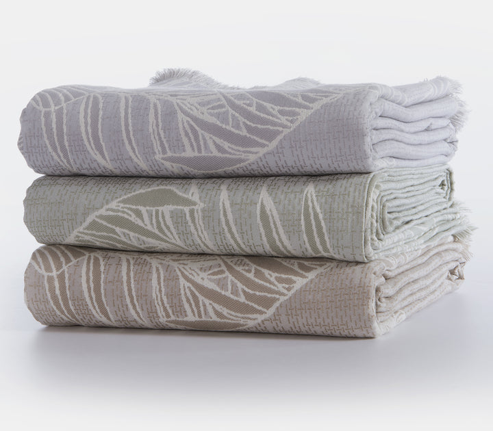 Τρία διπλωμένα ριχτάρια με φυλλωτό σχέδιο, σε γκρι, πράσινη και μπεζ απόχρωση αντίστοιχα.