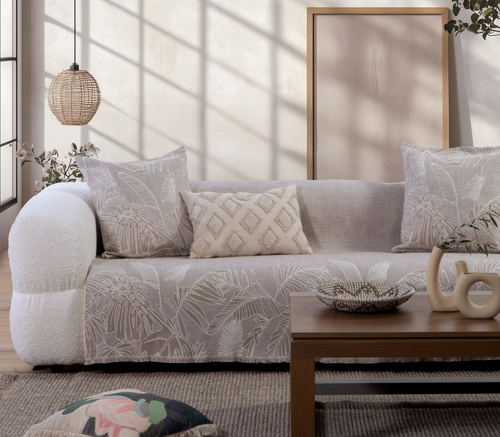 Ριχτάρι σε μπεζ απόχρωση με ανάγλυφο φυλλωτό σχέδιο σε εκρού χρώμα, στρωμένο σε καναπέ.
