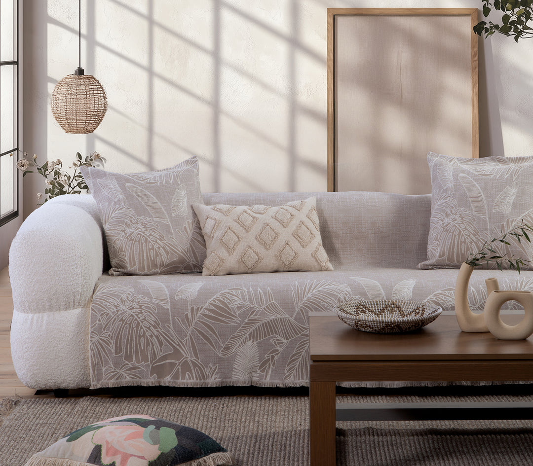 Ριχτάρι σε μπεζ απόχρωση με ανάγλυφο φυλλωτό σχέδιο σε εκρού χρώμα, στρωμένο σε καναπέ.