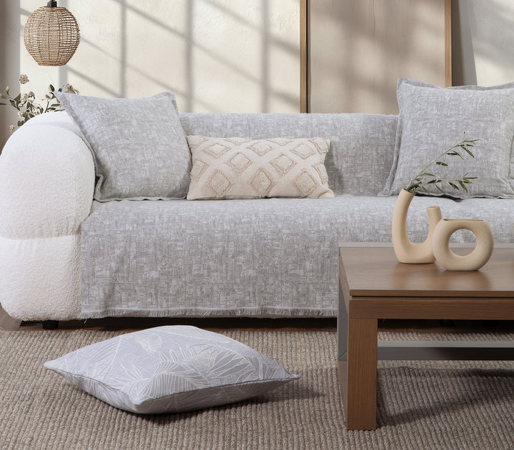 Ριχτάρι σε απαλή γκρι απόχρωση με γεωμετρικό ανάγλυφο σχέδιο, απλωμένο σε καναπέ.