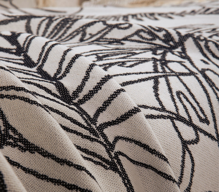 Κοντινή λήψη υφάσματος ριχταριού σε εκρού απόχρωση με μαύρο τροπικό σχέδιο