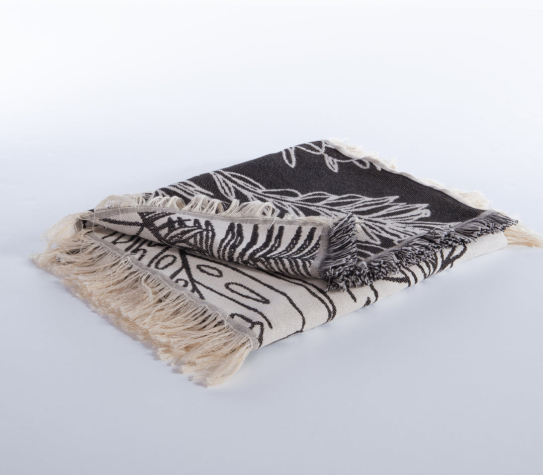 Ριχτάρι διπλής όψης με τροπικά σχέδια σε εκρού και μαύρη απόχρωση, διπλωμένο σε λευκό φόντο.