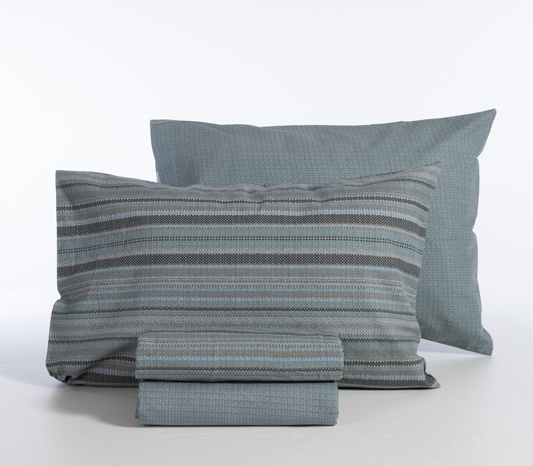 Σετ σεντόνια γαλάζια με γκρι και μαύρες ρίγες, διπλωμένα με μαξιλαροθήκες σε λευκό φόντο.