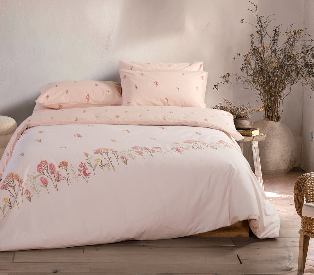 Ρομαντικό υπνοδωμάτιο με σετ σεντονιών σε εκρού απόχρωση, λουλουδάτα σχέδια και φυσικά διακοσμητικά στοιχεία στο φόντο.