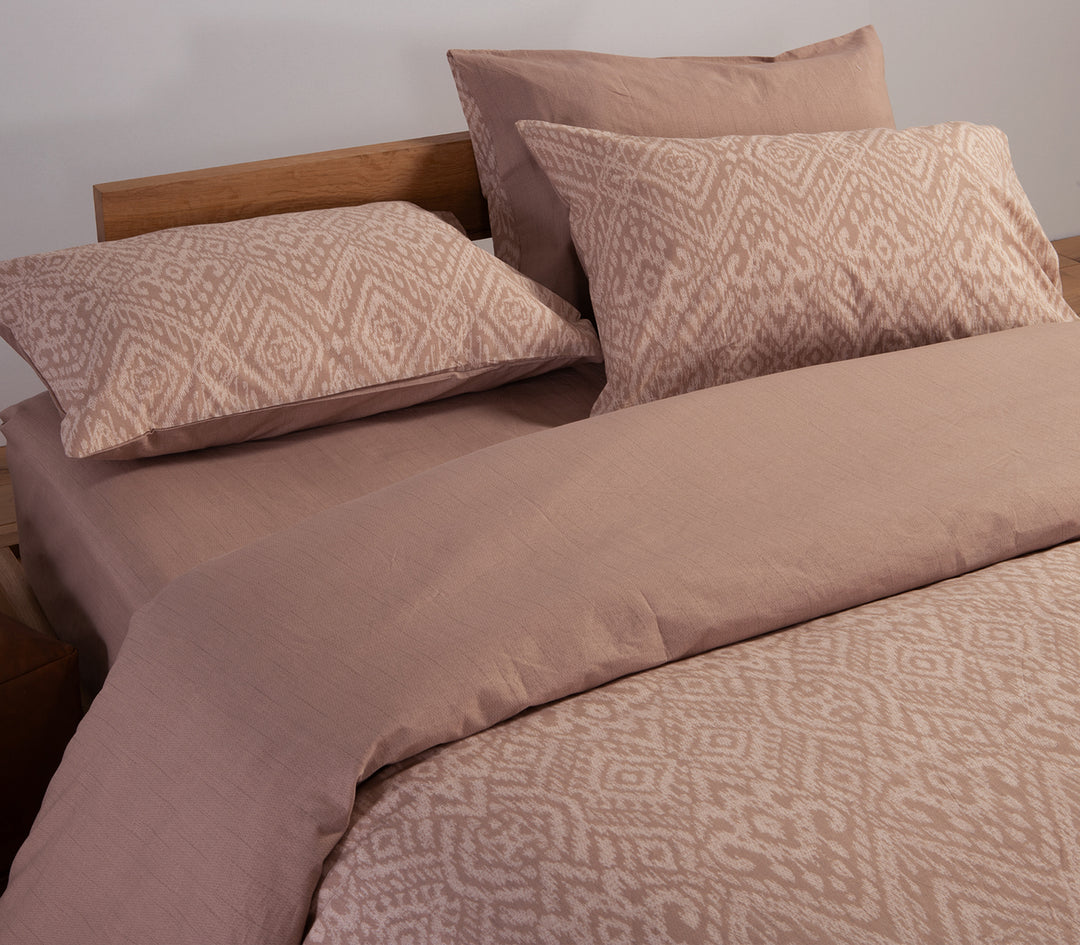 Κοντινή λήψη καφέ σετ σεντονιών με γεωμετρικά σχέδια και συνδυασμό με μονόχρωμο κατωσέντονο.