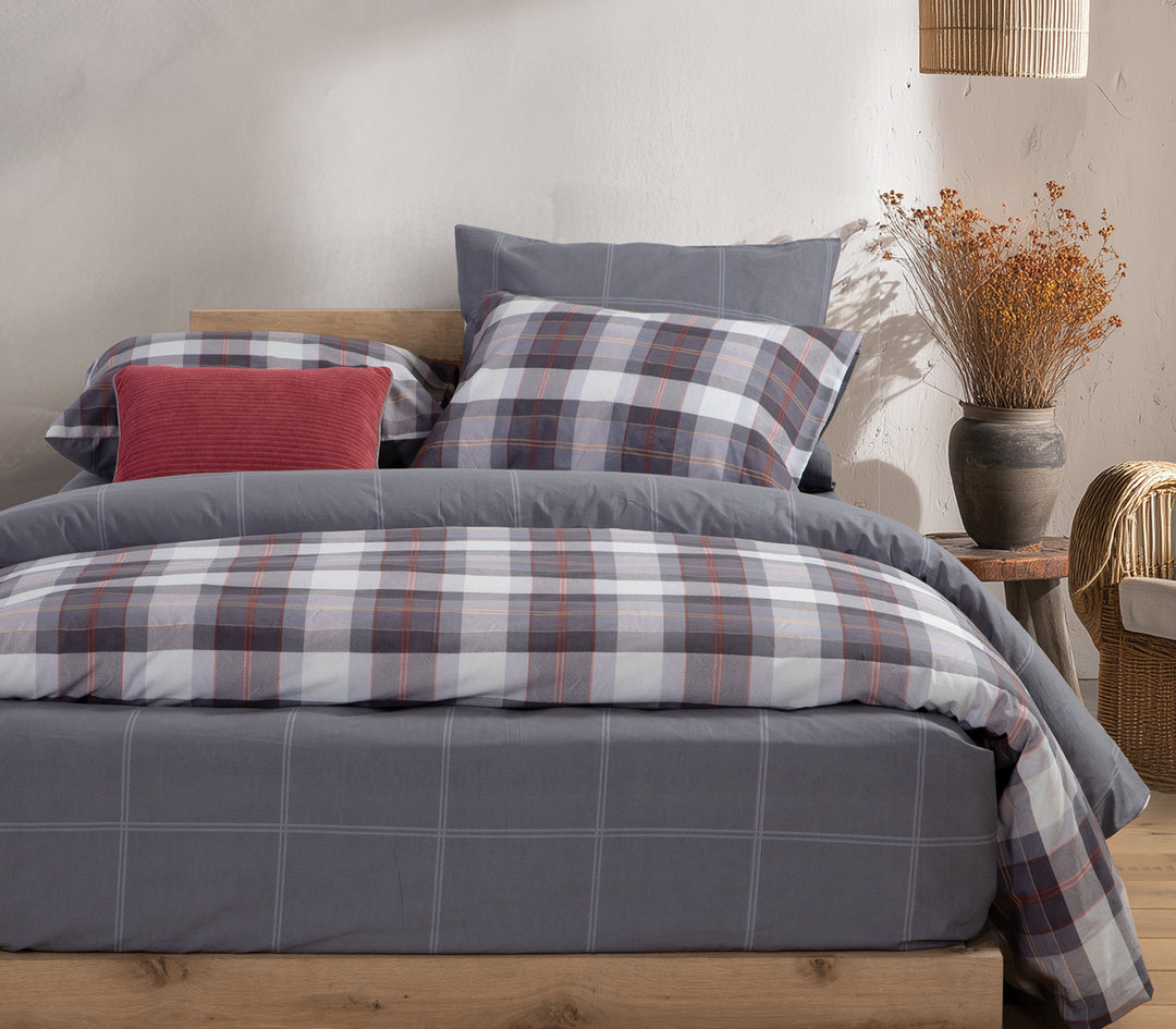 Υπνοδωμάτιο με μπλε καρό σετ σεντόνια και κόκκινο μαξιλάρι διακόσμησης.