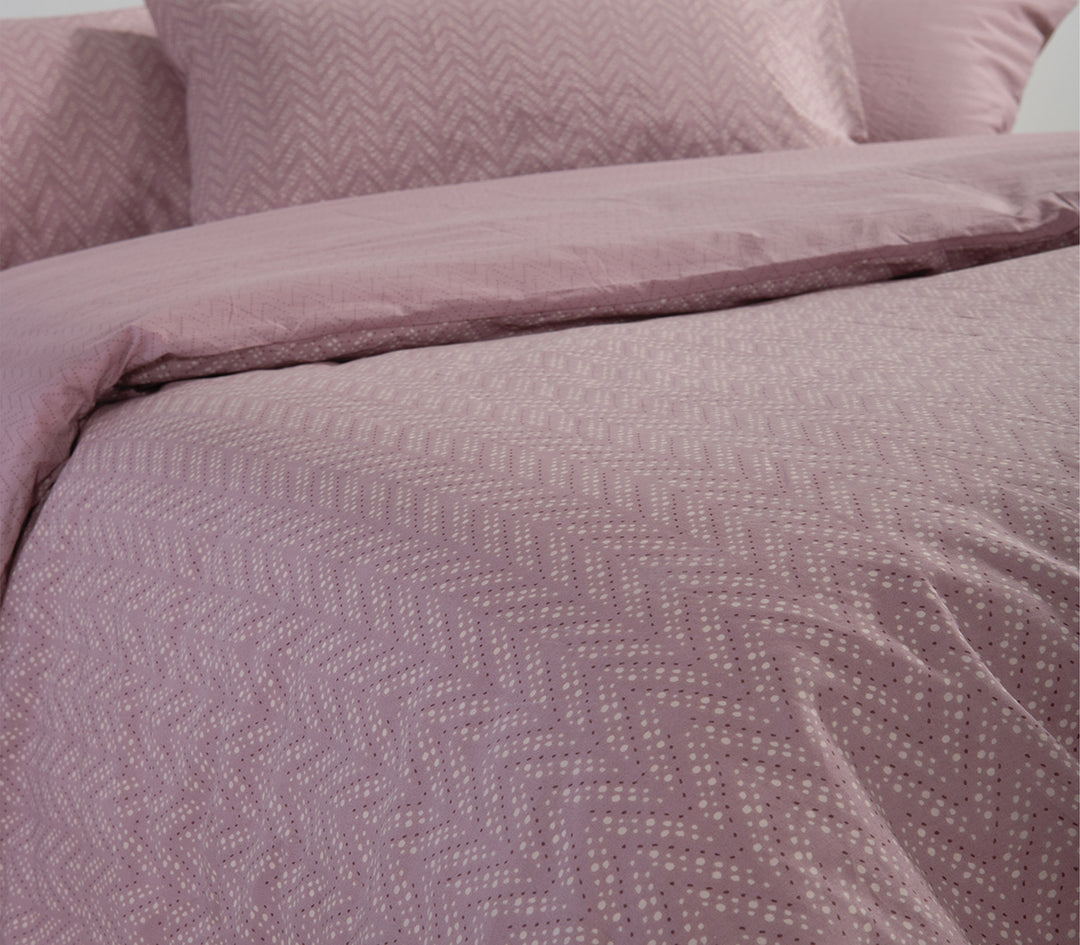 Λιλά σετ σεντονιών με λευκά πουά σε διακριτικό ζιγκ-ζαγκ μοτίβο, στρωμένο σε κρεβάτι.