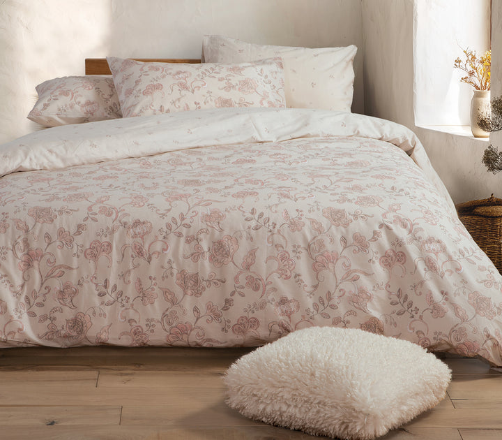 Υπνοδωμάτιο με εκρού σετ σεντόνια διακοσμημένα με απαλό ροζ λουλουδάτο μοτίβο.