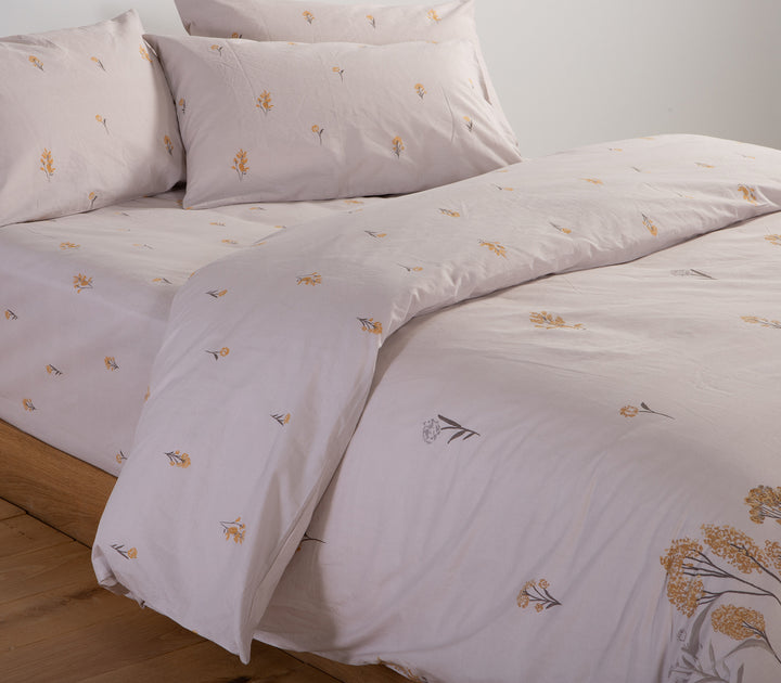 Κοντινή λήψη σε σετ σεντόνια σε απαλό γκρι με κίτρινα λουλούδια κεντημένα, μαξιλαροθήκες και κατωσέντονο.