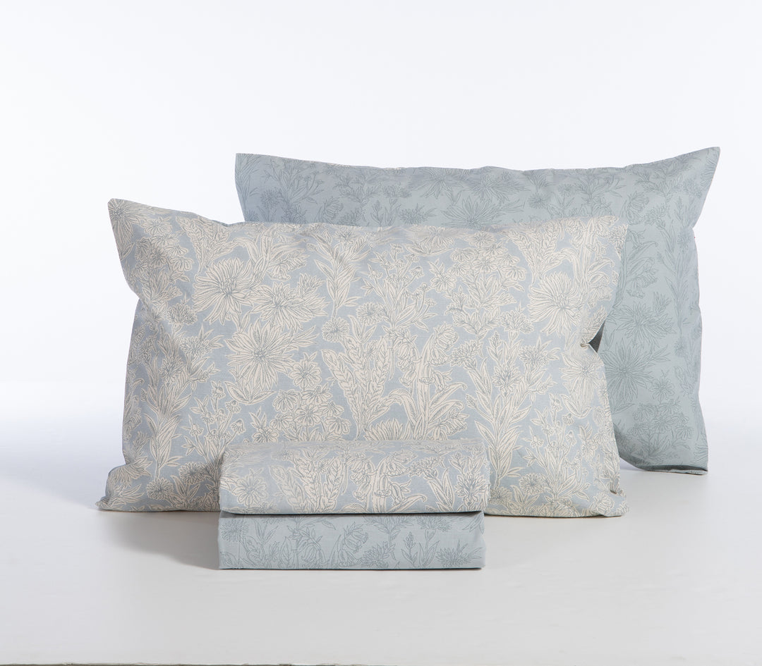 Σετ σεντόνια γαλάζιο με λουλουδάτο μοτίβο, διπλωμένα με μαξιλαροθήκες σε λευκό φόντο.