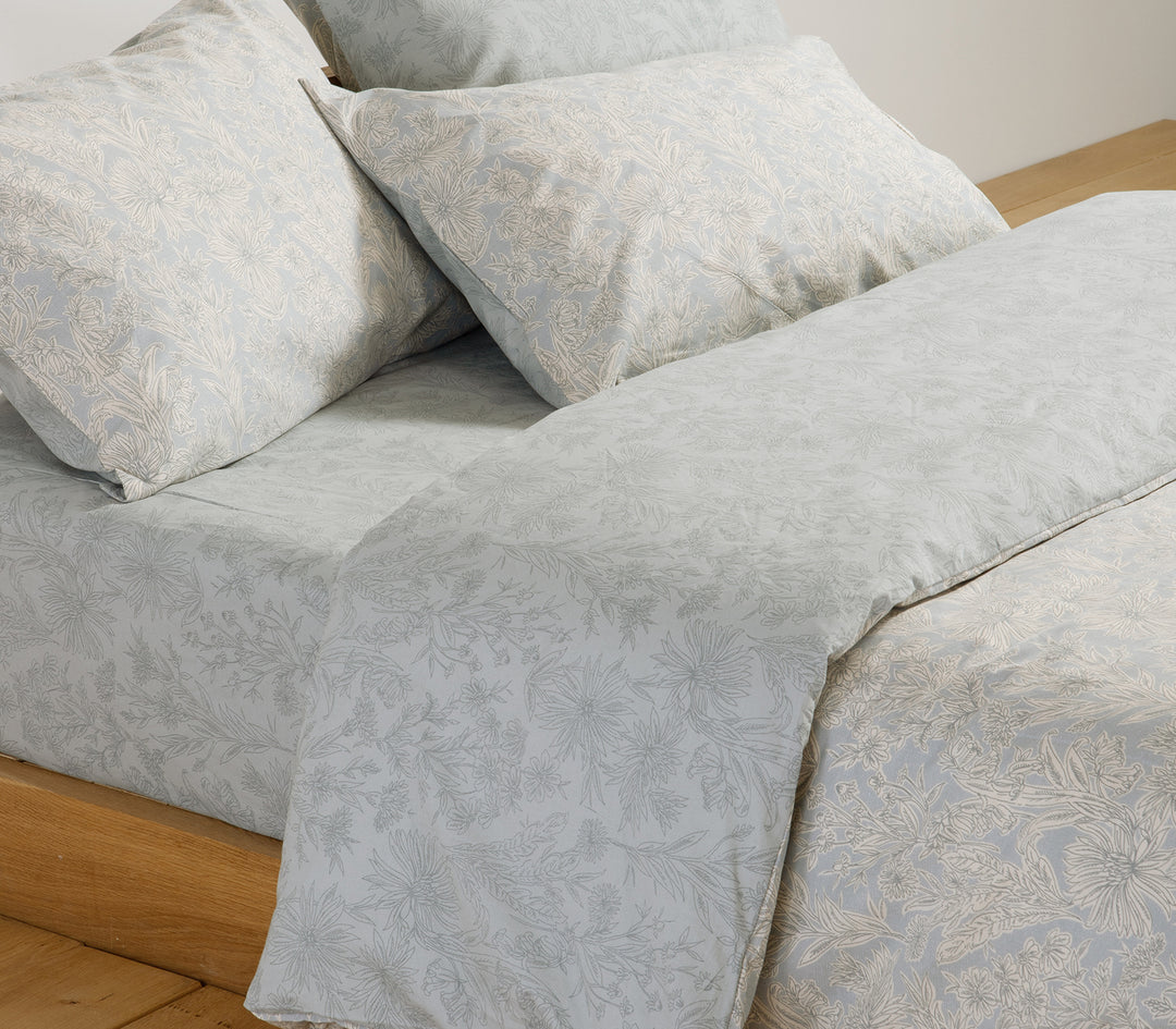 Κρεβάτι με γαλάζιο σετ σεντόνια λουλουδάτο σχέδιο σε μίνιμαλ υπνοδωμάτιο.