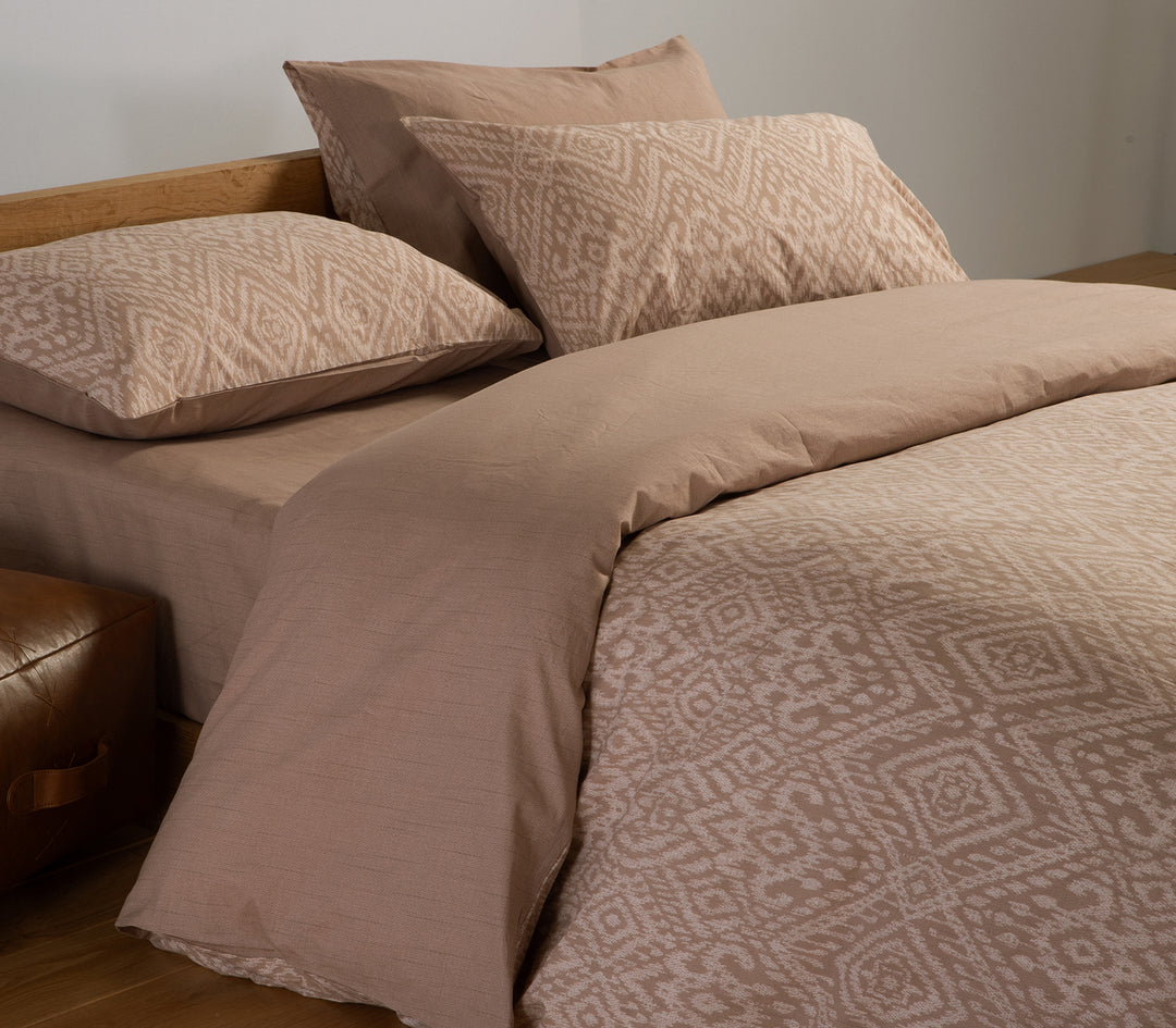 Κοντινή λήψη καφέ σετ σεντονιών με γεωμετρικά σχέδια και συνδυασμό με μονόχρωμο κατωσέντονο.