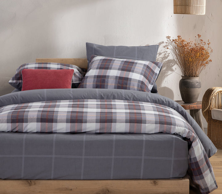 Υπνοδωμάτιο με μπλε καρό σετ σεντόνια και κόκκινο μαξιλάρι διακόσμησης.