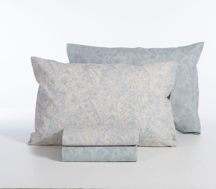 Σετ σεντόνια γαλάζιο με λουλουδάτο μοτίβο, διπλωμένα με μαξιλαροθήκες σε λευκό φόντο.