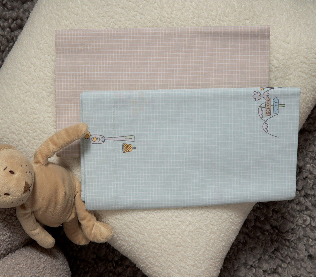Βρεφικά σεντόνια διπλωμένα, σε γαλάζιο και μπεζ με καρό μοτίβο. Το γαλάζιο σεντόνι έχει χαριτωμένα σχέδια με φωτεινό σηματοδότη, καλαθάκι και πινακίδα που γράφει "School City", ενώ το μπεζ παραμένει μινιμαλιστικό με το ίδιο καρό μοτίβο. Φωτογραφημένα πάνω σε απαλή φλοκάτη, δίπλα σε λούτρινο παιχνίδι.
