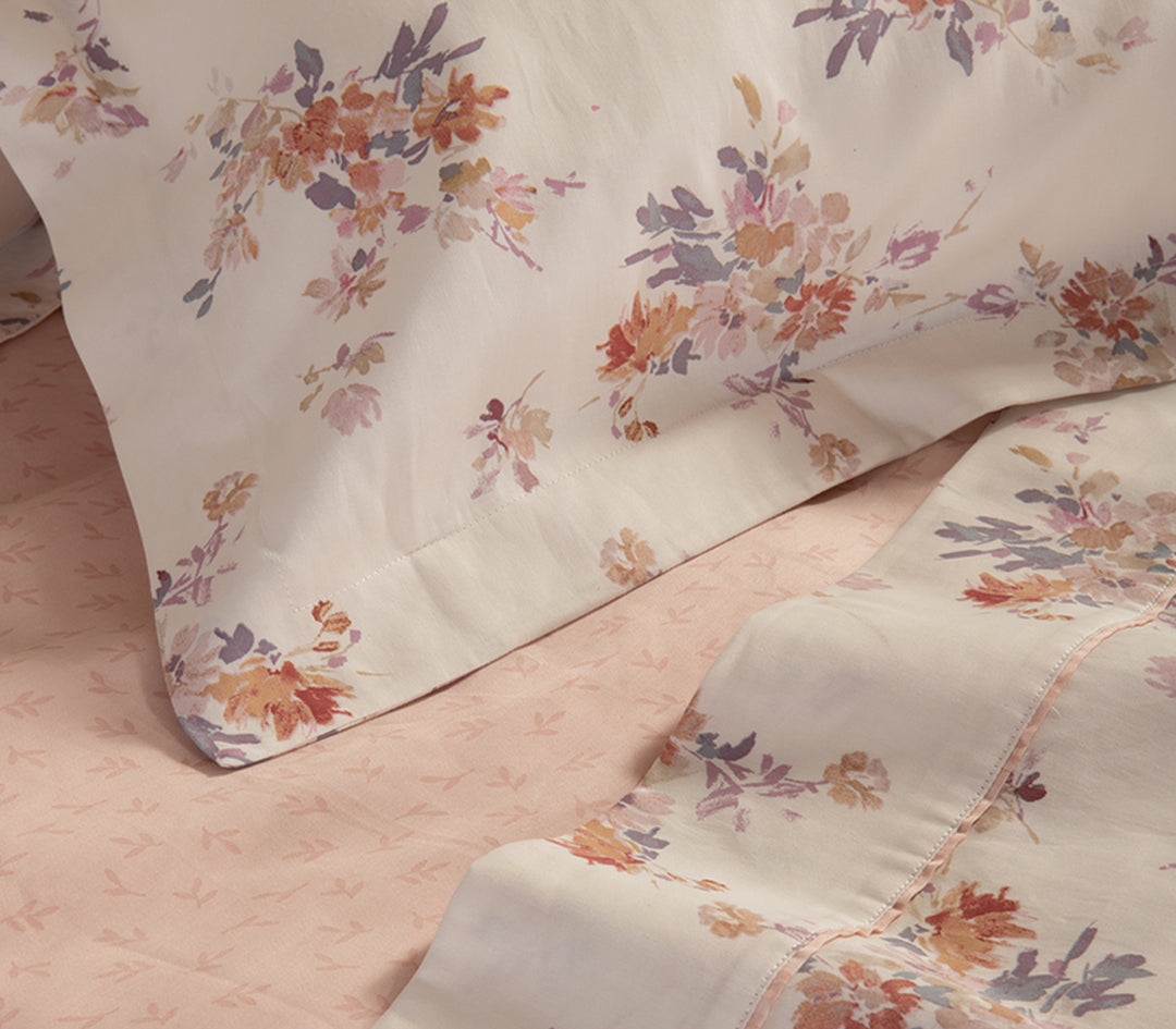 Κοντινή λήψη σε βαμβακερό σεντόνι με λουλουδάτο σχέδιο σε λευκή βάση και ροζ λεπτομέρειες.