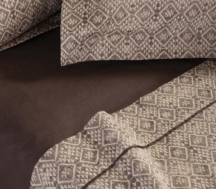 Λεπτομέρεια σεντονιών σε καφέ και μπεζ χρώμα με διακριτικό γεωμετρικό σχέδιο και καφέ κατωσέντονο.