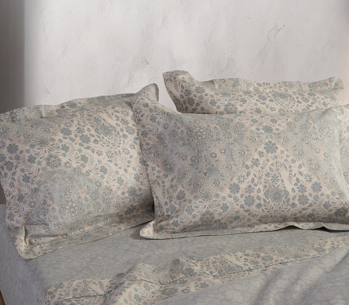 Κοντινή λήψη μαξιλαροθήκης και σεντονιού σε γκρι και εκρού χρώμα με διακριτικά φλοράλ σχέδια.