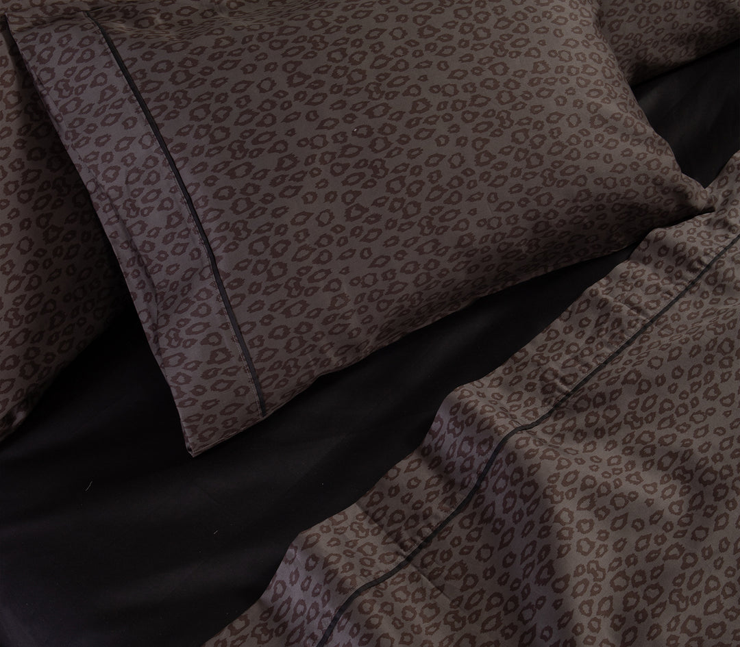Λεπτομέρεια από ανθρακί μαξιλαροθήκες και σεντόνια με leopard μοτίβο πάνω σε μαύρο κατωσέντονο.