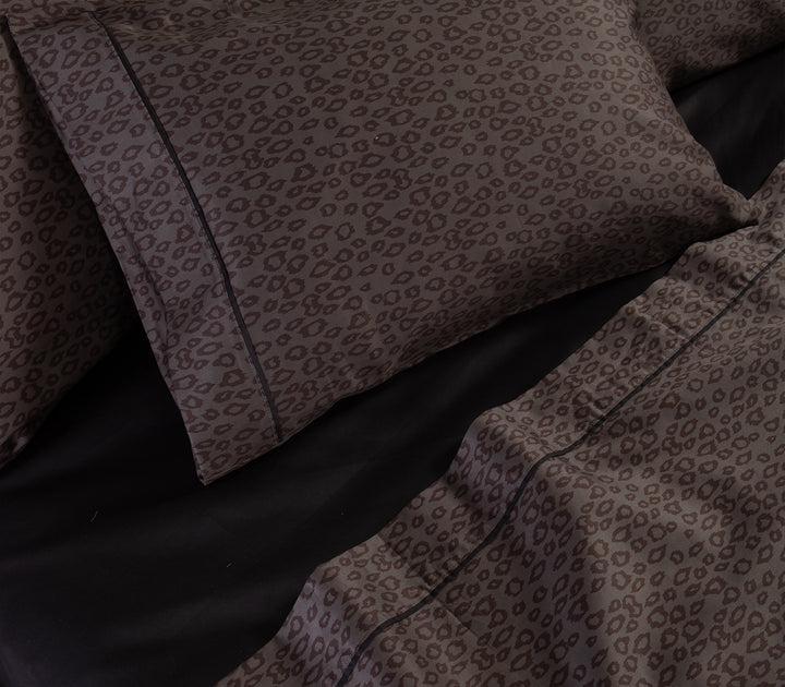 Λεπτομέρεια από ανθρακί μαξιλαροθήκες και σεντόνια με leopard μοτίβο πάνω σε μαύρο κατωσέντονο.