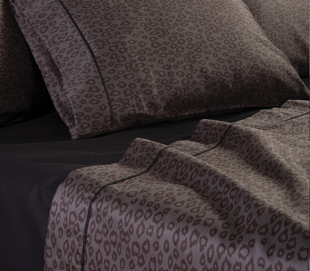 Λεπτομέρεια από μαξιλαροθήκες και σεντόνια με καφέ leopard μοτίβο σε μαύρο κατωσέντονο.