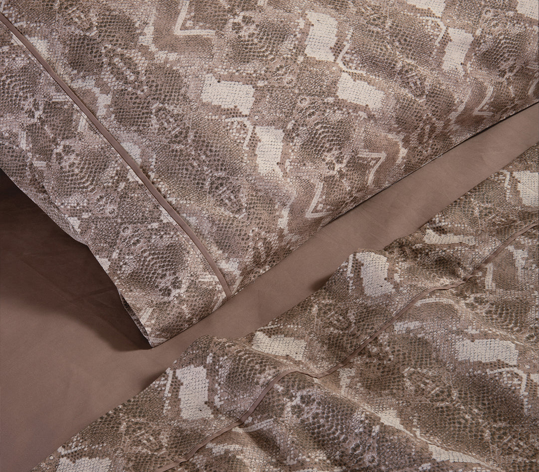 Λεπτομέρεια από καφέ μαξιλαροθήκη και σεντόνια με snake print σχέδιο.