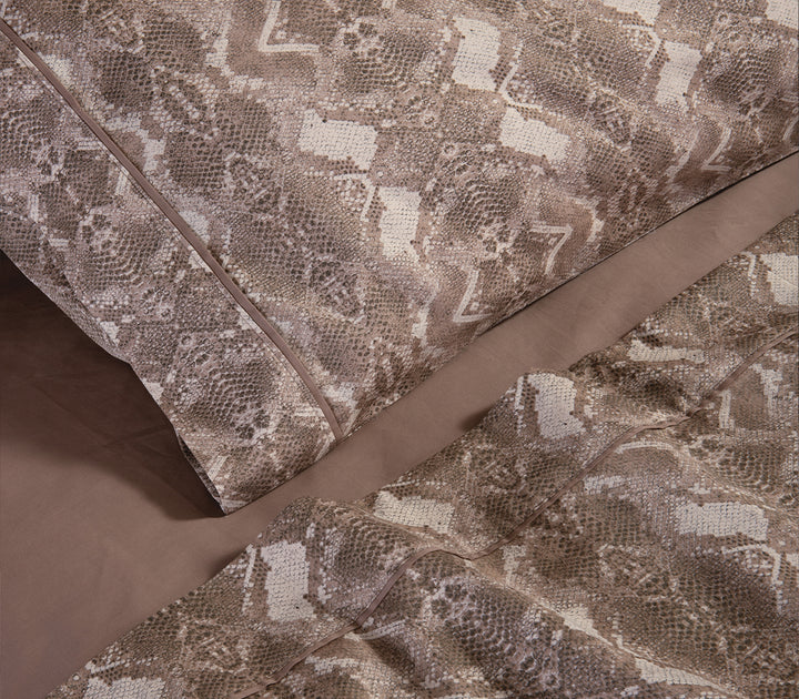 Λεπτομέρεια από καφέ μαξιλαροθήκη και σεντόνια με snake print σχέδιο.