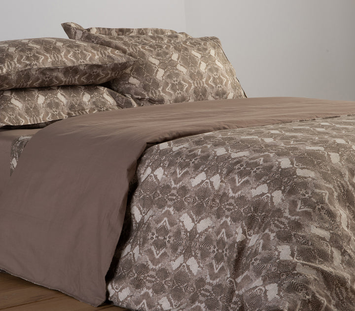 Καφέ παπλωματοθήκη με snake print σχέδιο και μαξιλαροθήκες σε κρεβάτι με μπεζ κατωσέντονο.