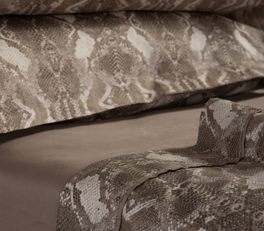 Κοντινή λήψη καφέ μαξιλαροθήκης και σεντονιών με snake print σχέδιο.