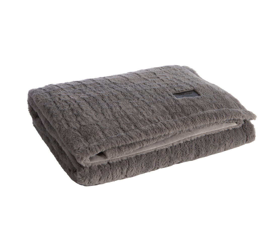 Διπλωμένη γκρι κουβέρτα με απαλή υφή και διακριτική ετικέτα.