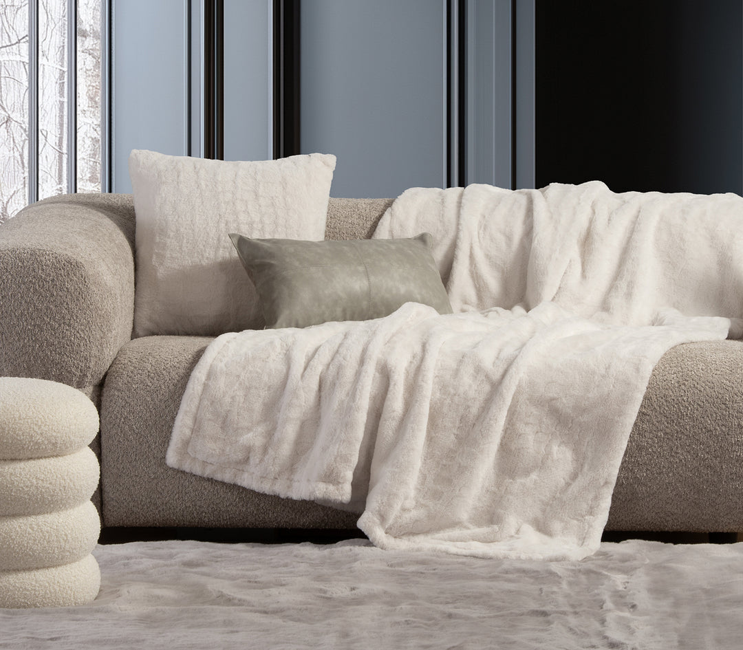 Στοίβα από τέσσερις γούνινες κουβέρτες σε μαύρο, καφέ, λευκό και γκρι χρώμα.