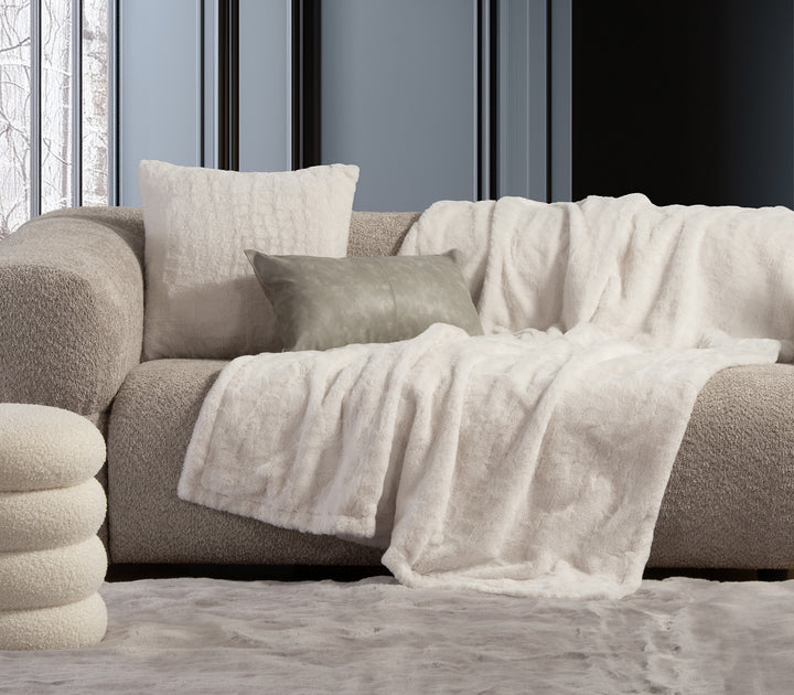 Στοίβα από τέσσερις γούνινες κουβέρτες σε μαύρο, καφέ, λευκό και γκρι χρώμα.