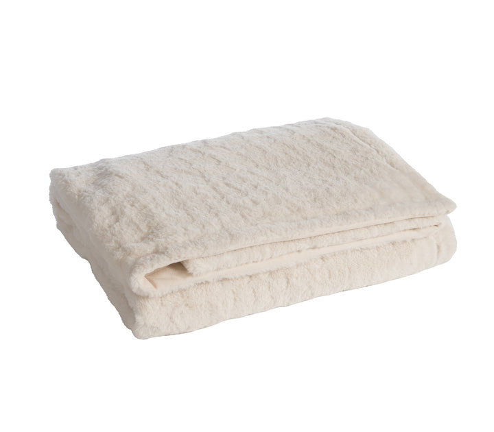 Λευκή γούνινη κουβέρτα με μαξιλάρι σε μπεζ καναπέ σαλονιού.