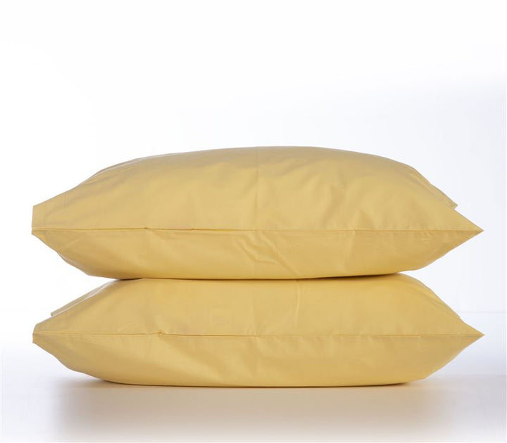Δύο κίτρινες μαξιλαροθήκες τοποθετημένες η μία πάνω στην άλλη, σε φωτεινό φόντο, με απλό και κομψό design.
