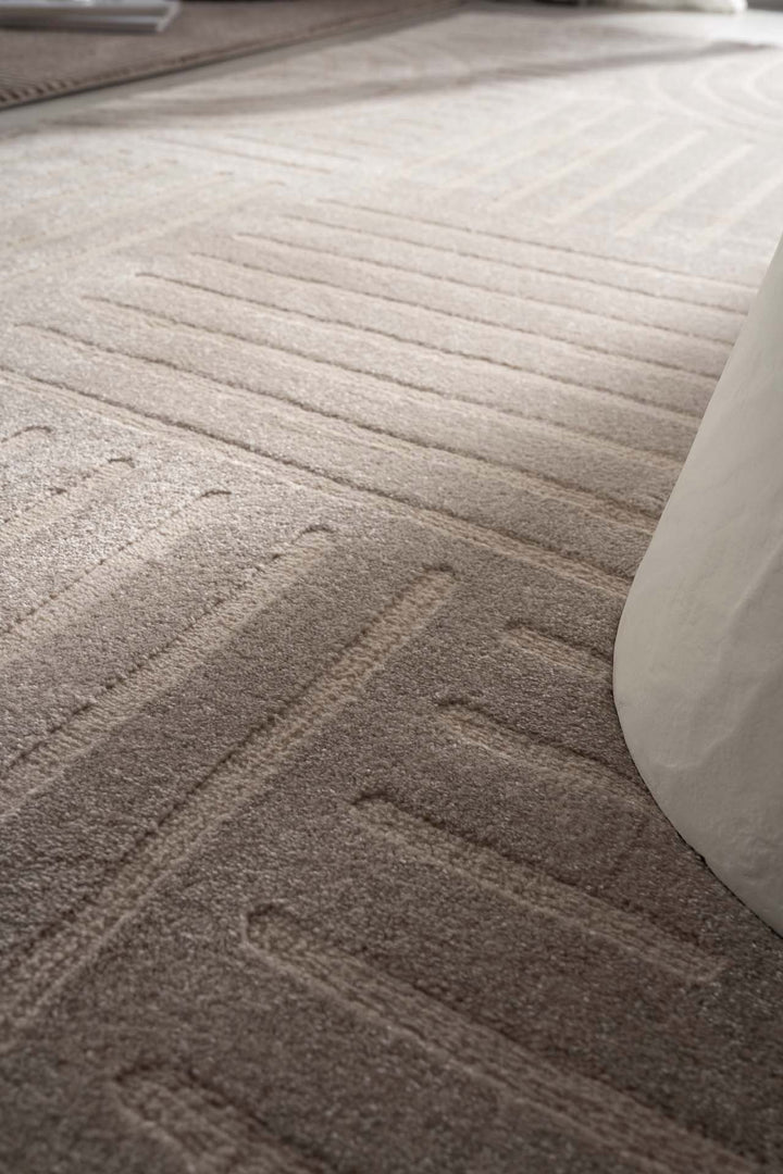 Πλάγια λήψη μπεζ χαλιού Organic Royal Carpet με καμπυλωτό γεωμετρικό μοτίβο και μαλακή υφή, ιδανικό για μοντέρνους χώρους.