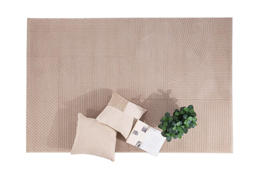 Χαλί Organic Royal Carpet σε μπεζ απόχρωση με γραμμικό μοτίβο, φωτογραφημένο από ψηλά με διακόσμηση μαξιλάρια και φυτό.