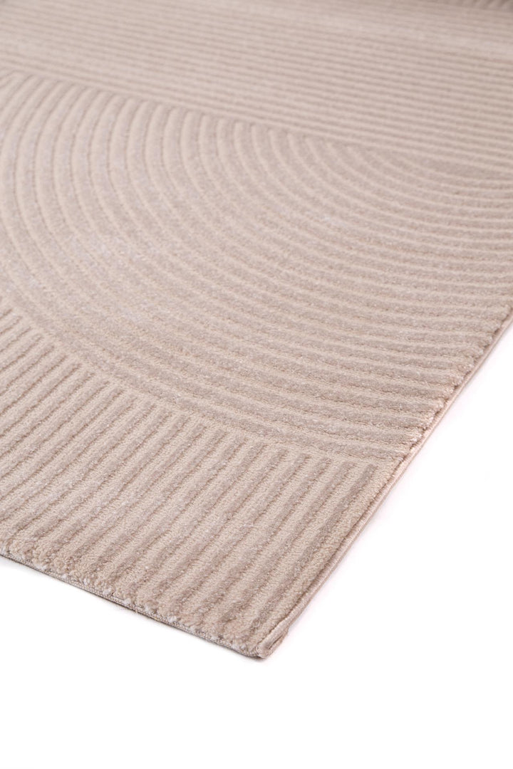 Κοντινή λήψη χαλιού Organic Royal Carpet σε μπεζ αποχρώσεις με κυκλικό και γραμμικό σχέδιο, λεπτομέρεια υφής στην άκρη του χαλιού.