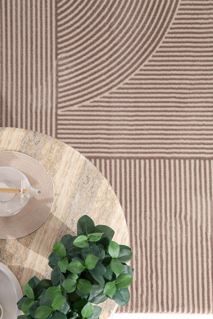 Μοντέρνο χαλί Organic Royal Carpet σε μπεζ τόνους με γεωμετρικά μοτίβα, διακοσμημένο με φυτά και μπεζ αξεσουάρ τραπεζιού.