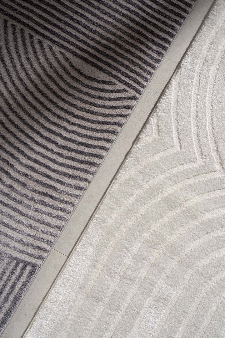 Δίχρωμο χαλί Organic Royal Carpet σε γκρι και εκρού, με κυκλικά και γραμμικά σχέδια, λεπτομέρεια από κοντινή λήψη στο πάτωμα.