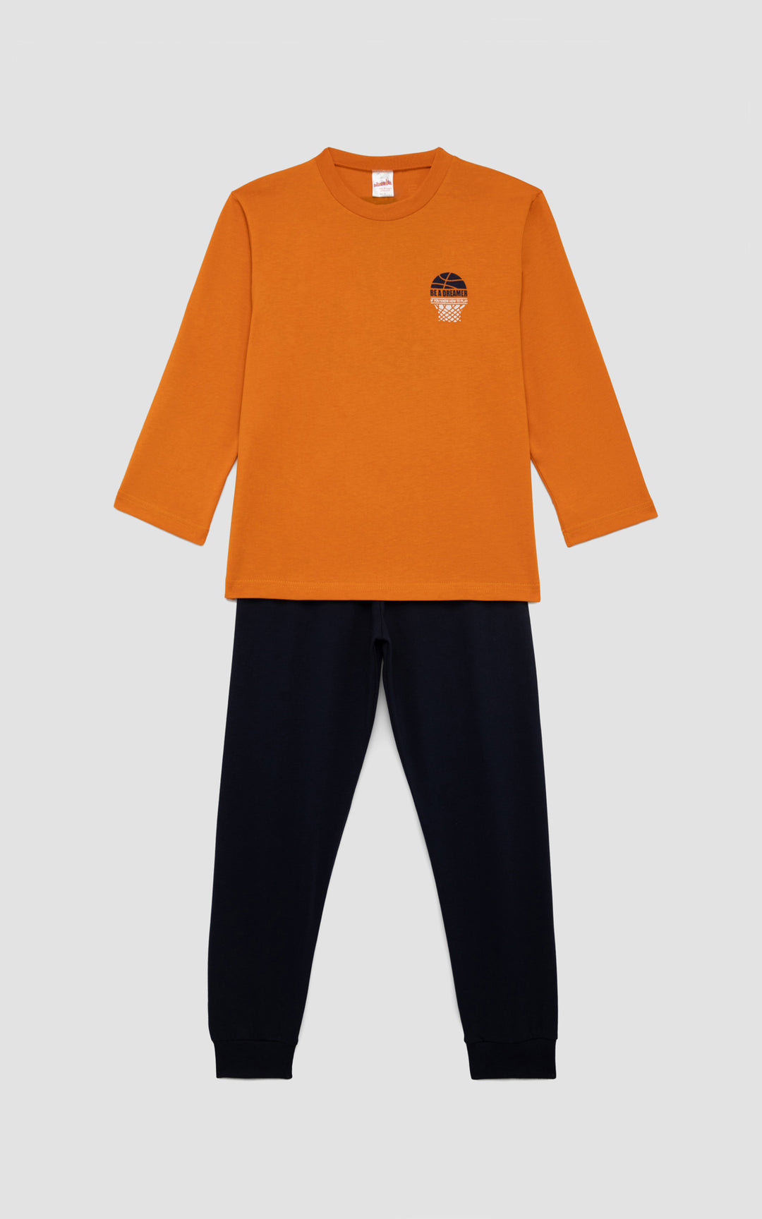 Παιδική πιτζάμα με πορτοκαλί μπλούζα και σχέδιο μπάσκετ στο στήθος, συνδυασμένη με μονόχρωμο μπλε παντελόνι, τοποθετημένη σε απαλό γκρι φόντο.
