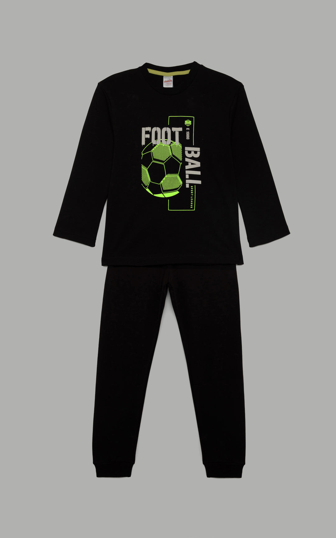 Μαύρη παιδική πιτζάμα με μακρυμάνικη μπλούζα και μοντέρνο σχέδιο ποδοσφαίρου σε λευκές αποχρώσεις στο μπροστινό μέρος. Το σετ είναι τοποθετημένο σε ουδέτερο γκρι φόντο