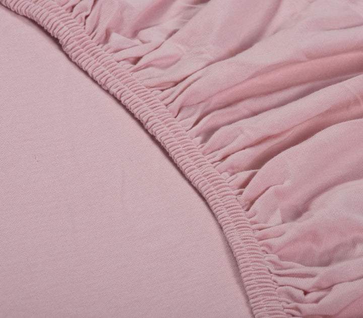 Κοντινό πλάνο σε ροζ βαμβακερό κατωσέντονο με λάστιχο, που δείχνει την εφαρμογή και την υφή του υφάσματος.