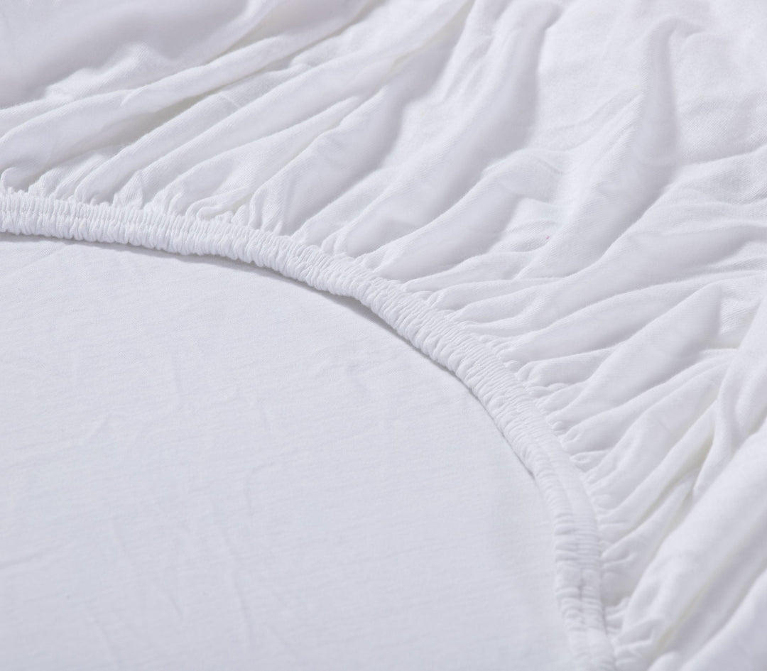 Λεπτομέρεια λευκού κατωσέντονου με λάστιχο, δείχνοντας την ελαστικότητα και τη ραφή στη γωνία.