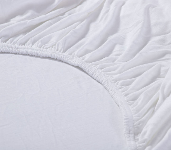 Λεπτομέρεια λευκού κατωσέντονου με λάστιχο, δείχνοντας την ελαστικότητα και τη ραφή στη γωνία.