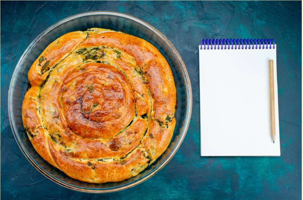 Σπανακόπιτα σε μορφή κέικ με σημειωματάριο και μολύβι για την καταγραφή των υλικών