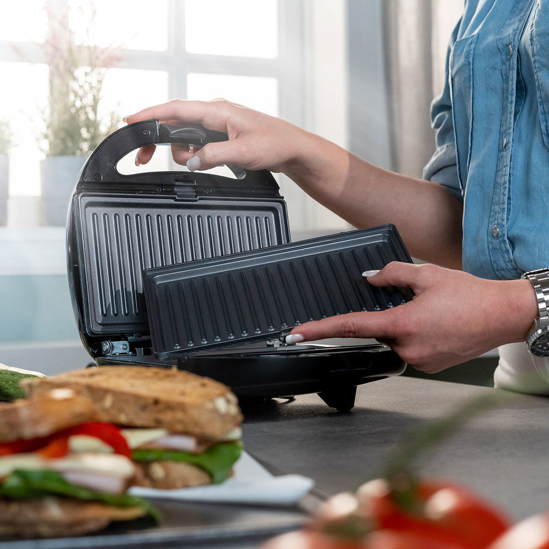 Τοστιέρα Estia Basics Black & Inox σε χρήση πάνω σε πάγκο κουζίνας, με ανοιχτές πλάκες και τοστ στο προσκήνιο.