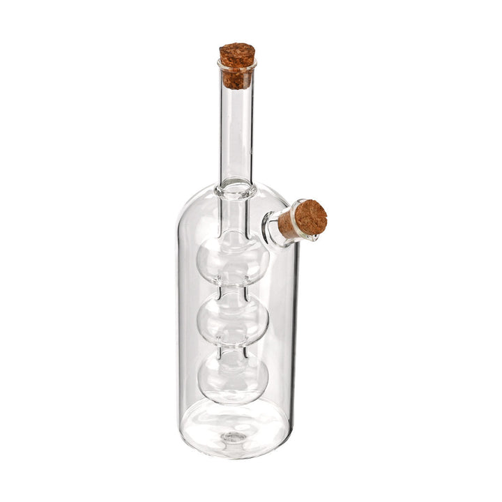 Πλάγια όψη από διάφανη γυάλινη φιάλη λαδιού με τριπλό εσωτερικό δοχείο και πώμα φελλού, σε λευκό φόντο.